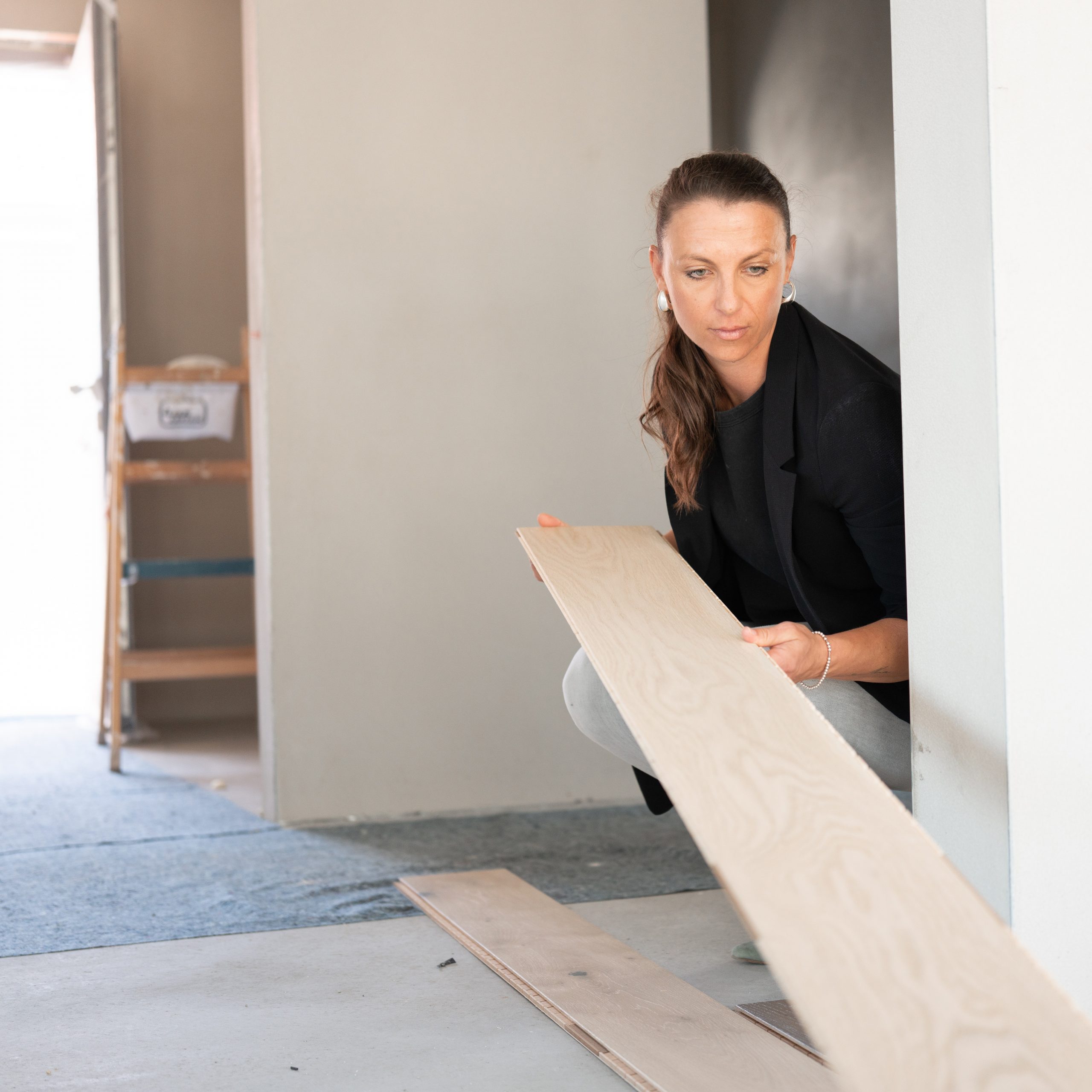 Interior Designerin und Lichtplanerin Tanja bei der Auswahl eines Holzbodens während einer Sanierung